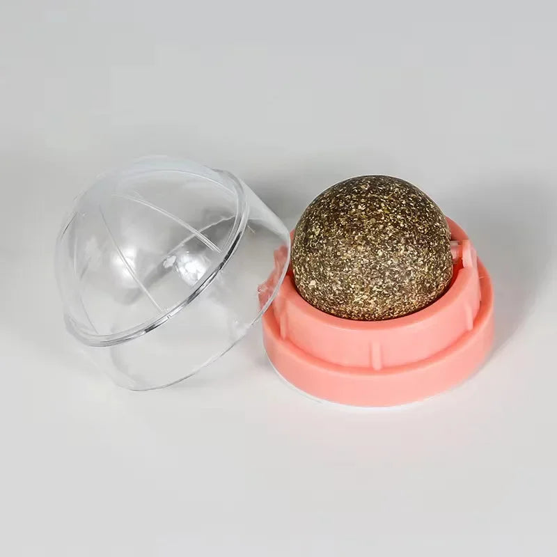 Gold glittery sphere in a pink container with a clear lid on a light gray background
