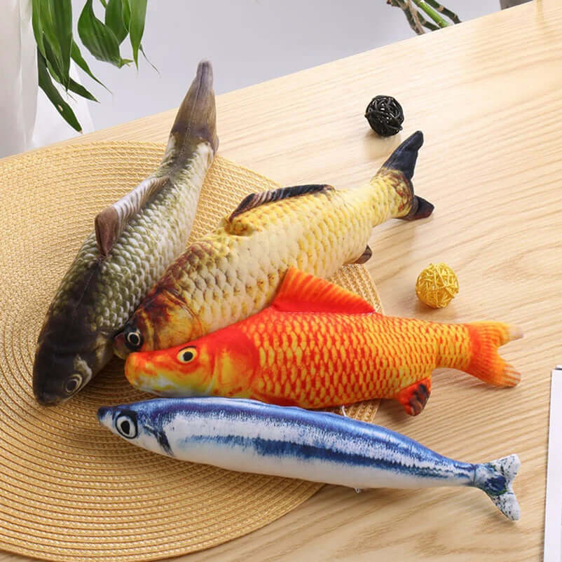 Four fish-shaped toys on a wooden surface with a straw hat and small items.