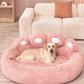 Dog lying on a pink fluffy pet bed in a living room.