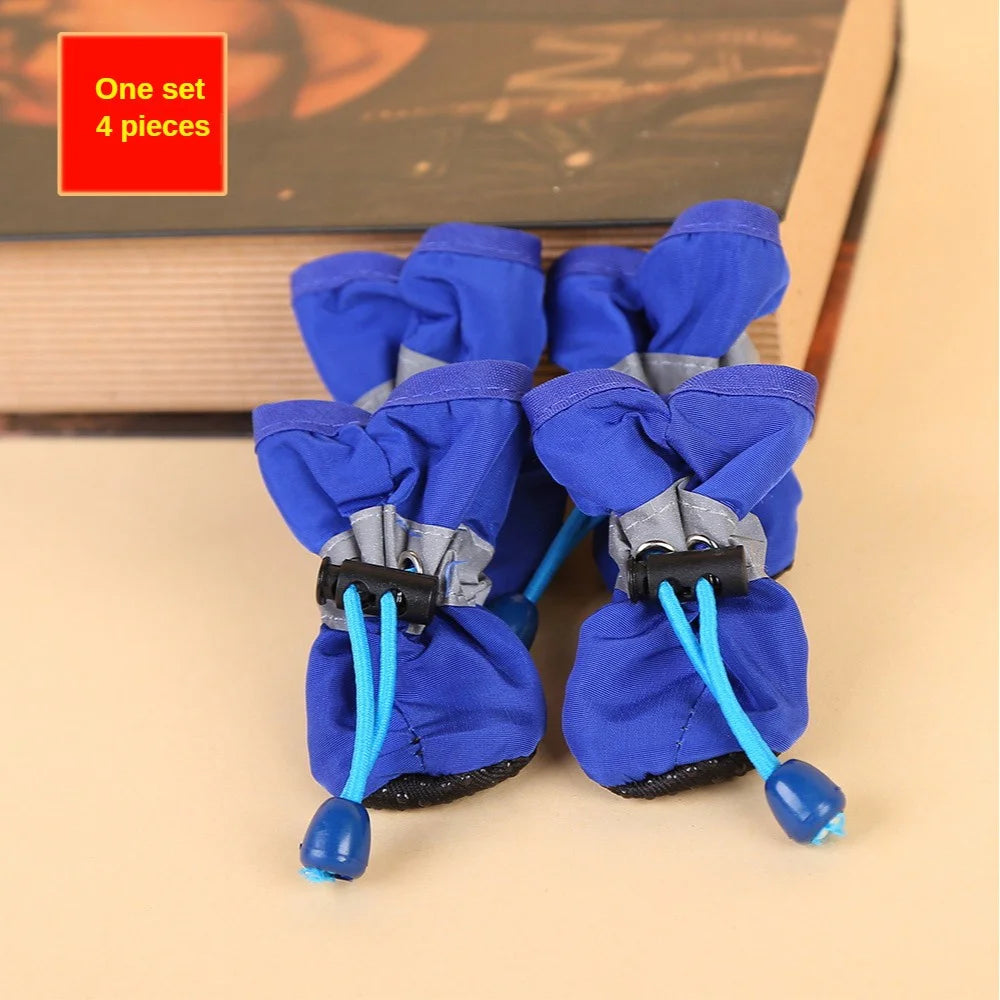 Set of four blue pet boots with blue straps on a beige surface.