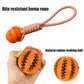 Orange dog toy with a rope and natural rubber ball, held in a hand.
