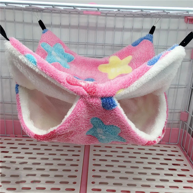 Pink pet hammock with star and butterfly patterns hanging inside a cage.