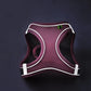 Purple dog harness with white accents on a dark background