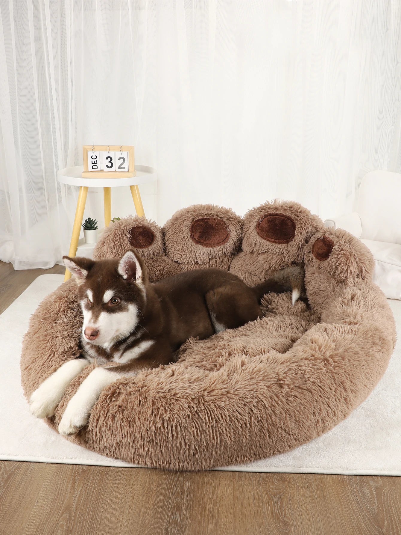 Dog lying on a fluffy paw-shaped pet bed with a white curtain background