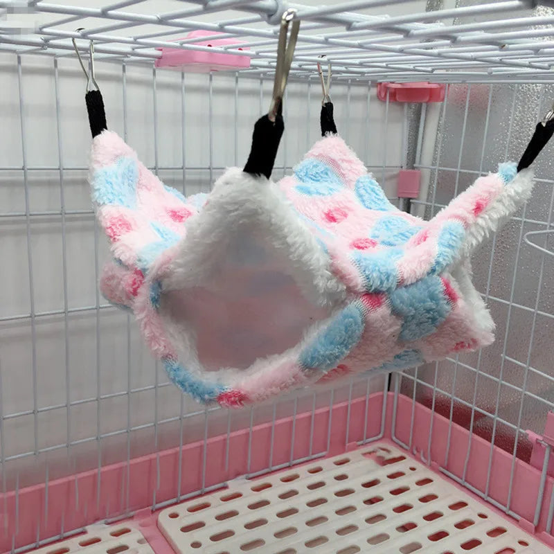 Plush pink, blue, and white pet hammock hanging in a pet cage.
