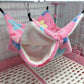 Pink pet hammock with colorful patterns hanging inside a pet cage.