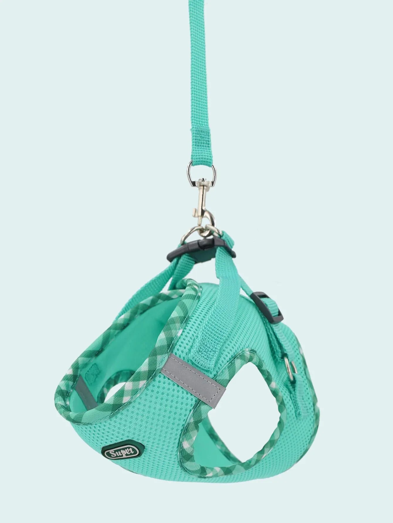 Turquoise dog harness with a checkered pattern on a light blue background