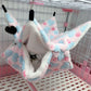 Floral-patterned pet hammock hanging inside a cage with a small animal peeking out.