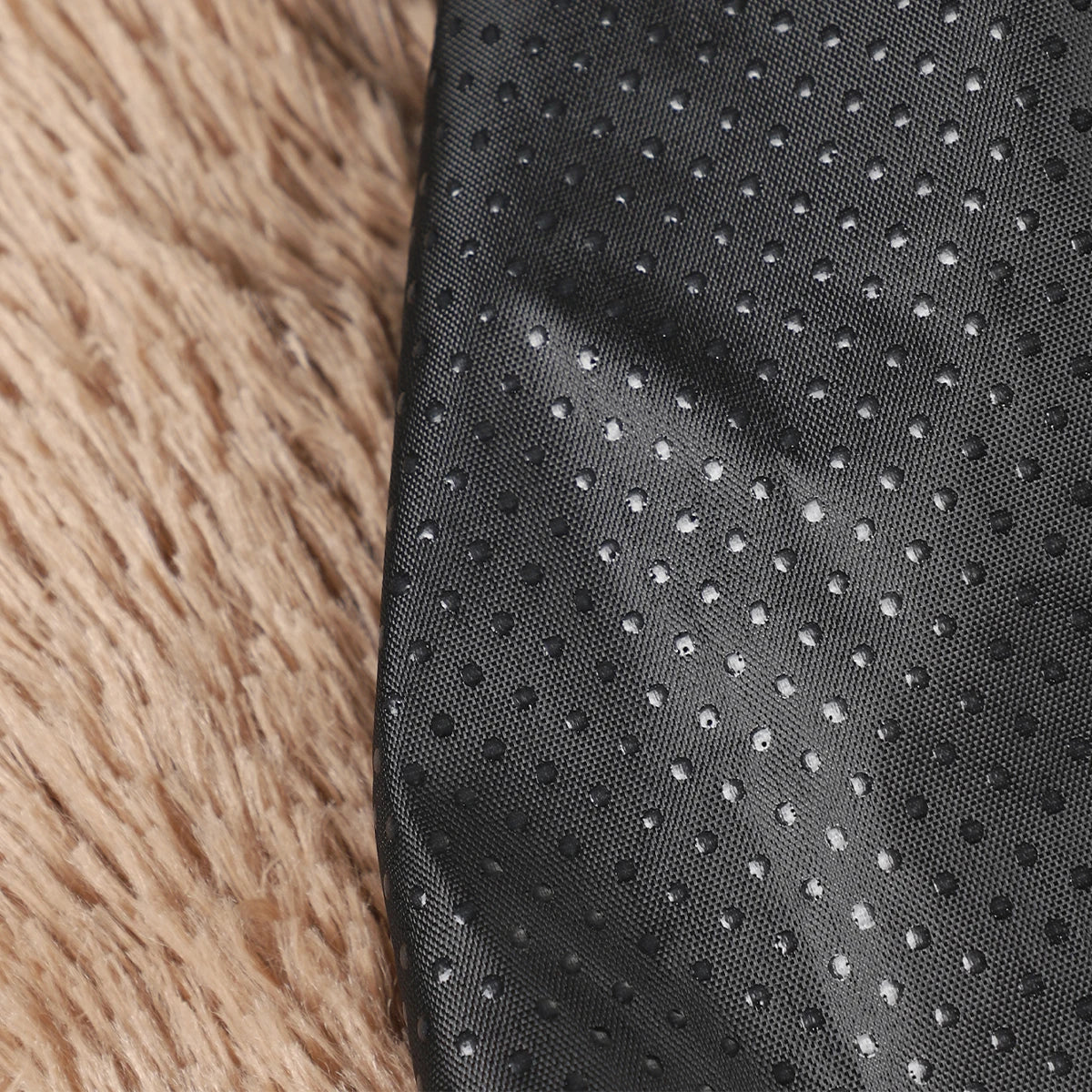 Close-up of black textured fabric on a fluffy beige surface