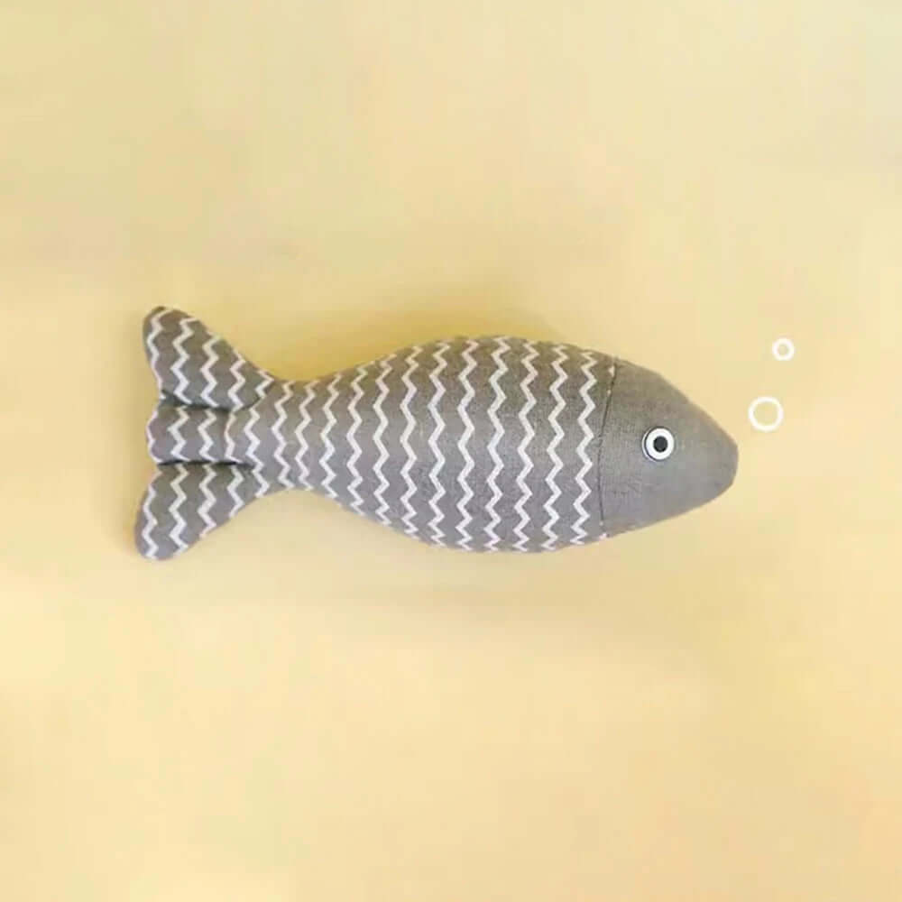 Gray fish-shaped plush toy on a beige background