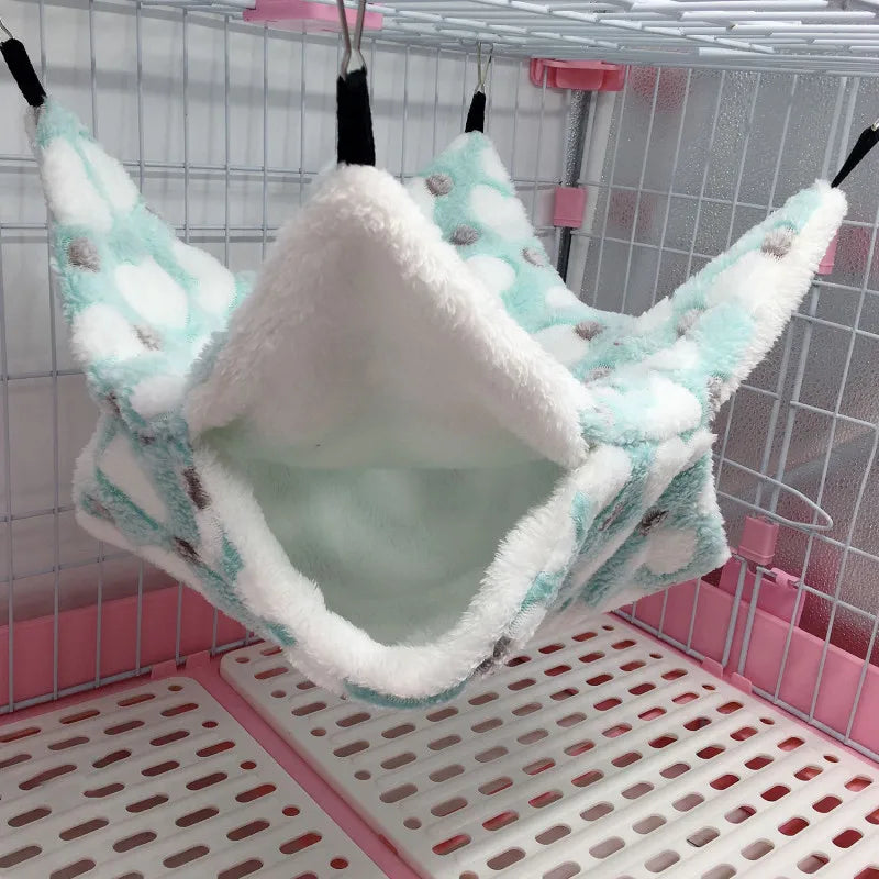 Pet hammock hanging inside a cage with a white and pink base.