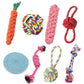 Assorted dog toys including a carrot-shaped toy, rope balls, and other chew items on a white background.