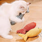 White cat playing with red and yellow striped fish-shaped toys on a wooden floor.
