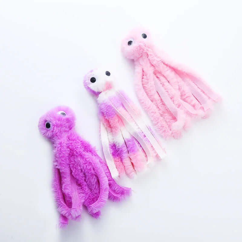 Three plush toy octopuses in pink, purple, and white on a white background