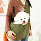 Person holding a white dog in a green pet sling against a neutral background