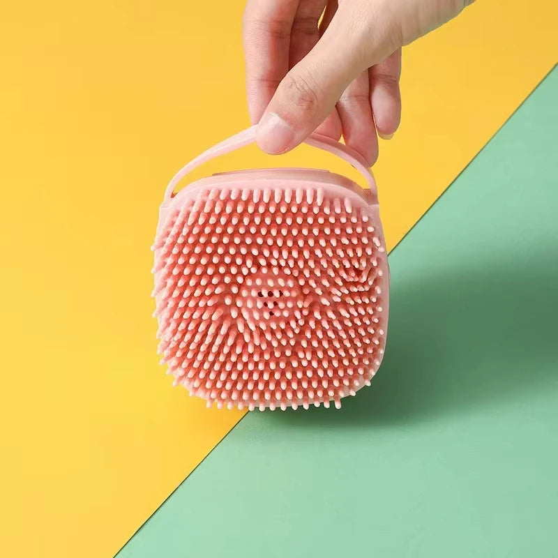 Pink silicone scrubber held by a hand on a yellow and green background