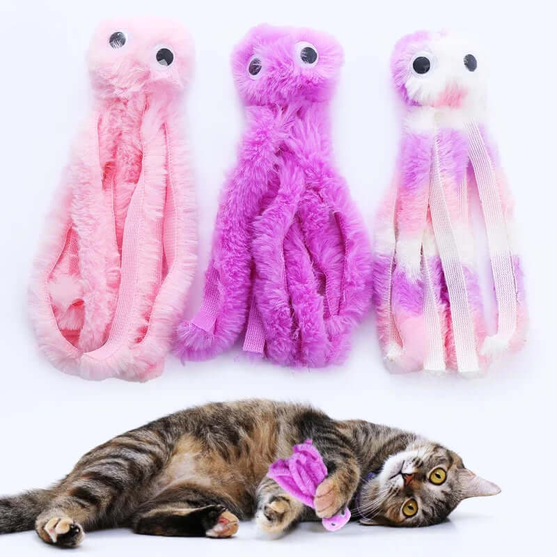 Three plush toy octopuses in pink, purple, and gradient colors with a cat interacting with one of them on a white background.