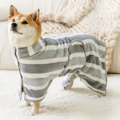 Dog wearing a gray and white striped robe on a soft surface