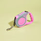 Pink and gray retractable dog leash on a light yellow background