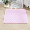 Pink quilted mat on a wooden floor with a white lace curtain in the background.