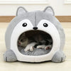Gray pet bed shaped like a cartoon character with a cat inside on a wooden floor.