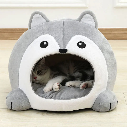 Gray pet bed shaped like a cartoon character with a cat inside on a wooden floor.